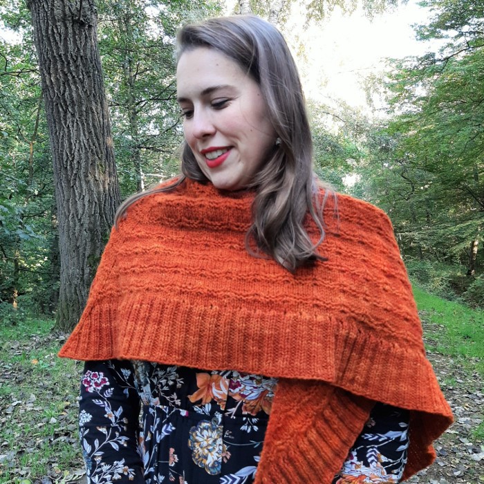 A triangular shaped shawl with a beautiful cable pattern and a ribbed edge decorated with eyelets.
