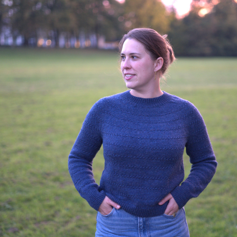 A blue sweater which is mainly Stockinette interrupted by stripes of star stitch.