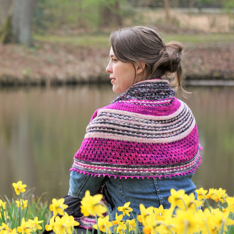 A crescent shaped shawl knit from hand-dyed yarn in three colors.