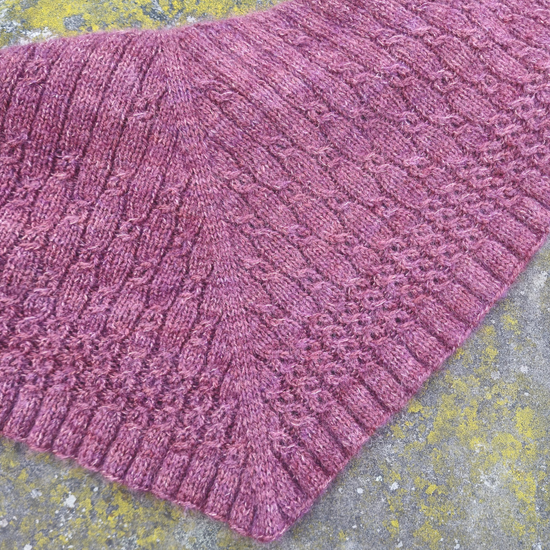 A triangular shawl with a delicate cable and eyelet pattern.
